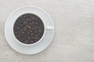 Obraz na płótnie Canvas White mug with coffee beans. Light textured background, toned photo. Copy space