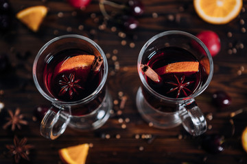 Mulled wine with spices and fruits on wooden background