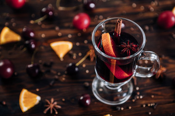 Mulled wine with spices and fruits on wooden background