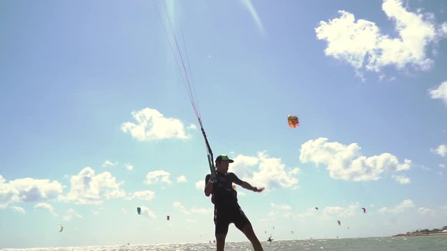 The man in the cap is holding one hand for the kiteboard rod and lands on the water, slow motion