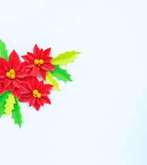 Paper flower poinsettia and leaves of holly