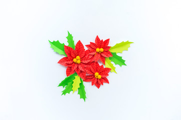 Paper flower poinsettia and leaves of holly