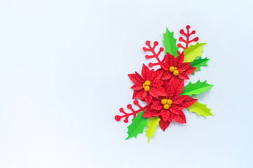 Paper flower poinsettia and leaves of holly