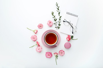Rose flowers with cup of tea and macaron on white background