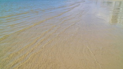 The waves beat at the beach with sand and reflection of sunlight in summer morning. Nature background concept.