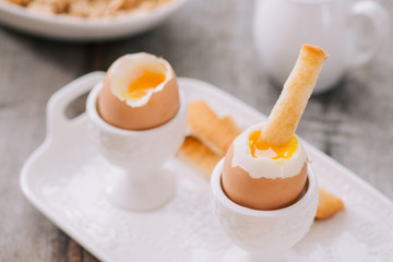 delicious breakfast with soft boiled eggs and crispy toasts, closeup