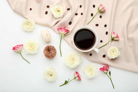 Rose flowers with cup of coffee and satin fabric on white background