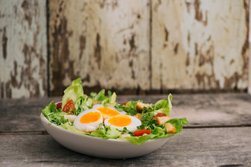 High Angle View of a Nutritious Vegetable Salad with Boiled Egg Slices, Served on a White Plate on Top of a Wooden Table