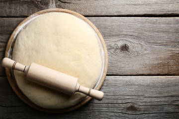 Raw dough with rolling pin on grey wooden table