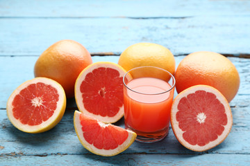 Ripe grapefruits and glass of juice on blue wooden table