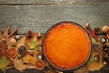 Pumpkin tart with dry leafs on wooden table