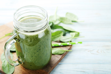 Spinach smoothie in glass jar on wooden table
