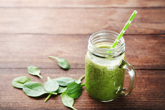 Spinach smoothie in glass jar on brown wooden table