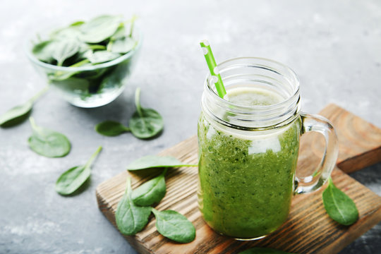 Spinach smoothie in glass jar on grey wooden table