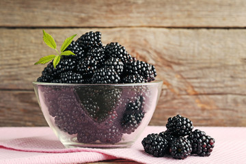 Ripe blackberries in glass bowl on wooden table