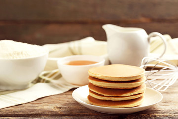 Tasty pancakes with flour and cup of tea on grey wooden table