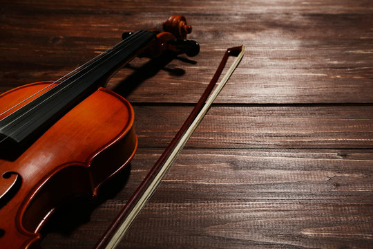 Violin with bow on brown wooden table