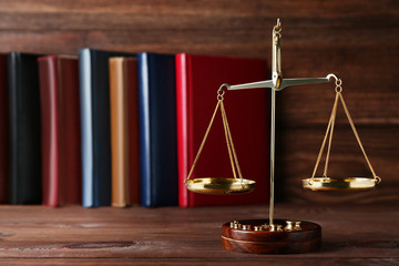 Scales of justice with books on brown wooden table