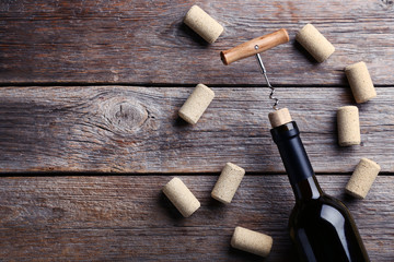 Wine bottle with corks and corkscrew on grey wooden table