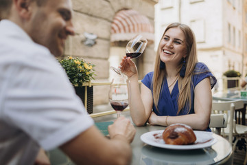 Young couple with glasses of red wine in a restaurant .