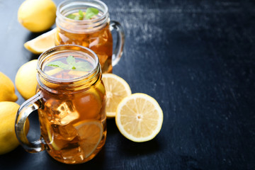 Ice tea in glass jars with lemon on wooden table