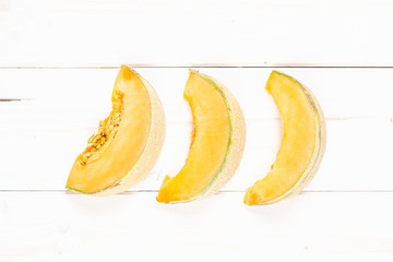 Group of three slices of fresh melon cantaloupe variety flatlay on grey wood