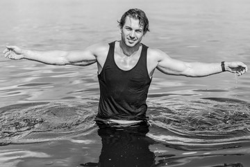 Handsome man in water, sexy guy showing muscular fit body. Concept os sport life of men. Muscular male bodybuilder torso on a sunny day at the beach 