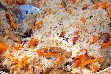 Big cauldron of asian pilaf, cooked from white rice with different vegetables and meat. Pilaf close up