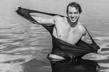 Handsome man in water, sexy guy showing muscular fit body. Concept os sport life of men. Muscular...