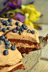 Cake brownie with cream and bilberries on a wooden background