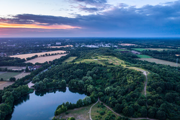 Obraz premium Aerial view of amazing sunset over the park in Germany. Hill and lake from birds eye view. 