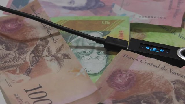 Physical metal Bitcoin currency over bolivar bills. Virtual internet money with Venezuelan banknotes. Digital coin cyberspace, cryptocurrency. BTC golden coin as symbol of electronic virtual money. 4K