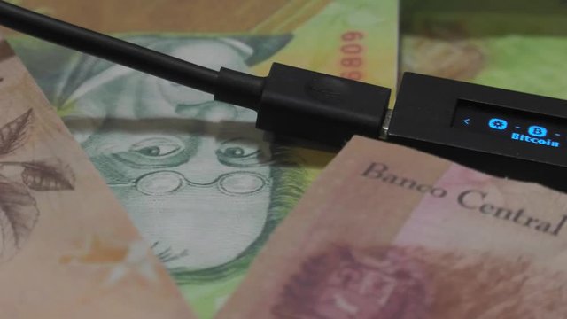 Physical metal Bitcoin currency over bolivar bills. Virtual internet money with Venezuelan banknotes. Digital coin cyberspace, cryptocurrency. BTC golden coin as symbol of electronic virtual money. 4K
