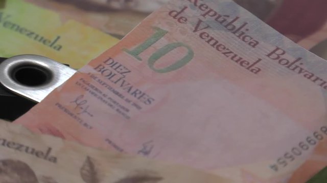 Physical metal Bitcoin currency over bolivar bills. Virtual internet money with Venezuelan banknotes. Digital coin cyberspace, cryptocurrency. BTC golden coin as symbol of electronic virtual money. 4K