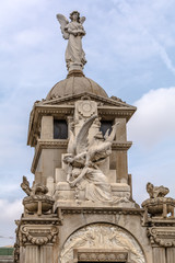 Obraz premium Crypt with amazing sculptures against the blue sky in Poblenou Cemetery in Barcelona, Spain. Peaceful but macabre, cemetery of Poblenou is today home to incredible sculptures, haunting, yet beautiful.