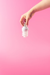 close-up partial view of person holding light bulb isolated on pink