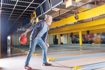 Fototapeta premium Favourite activity. Nice bearded man playing bowling while enjoying the activity