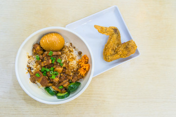 Braised pork rice and egg and in sweet brown sauce with fried chicken wings delicious food in Singapore on wooden table