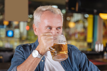 Time to relax. Joyful elderly man visiting a pub while resting at the weekends