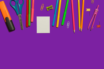 row of various school and office supplies and gadgets lying on a purple background. free space for advertising text