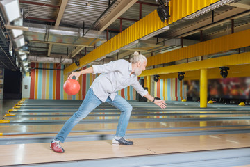 Obraz premium Favourite entertainment. Nice aged man holding a bowling ball while enjoying the game
