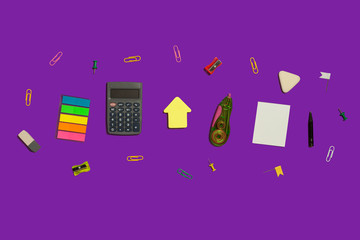 multiple school and office suplies and gadgets lying diagonally on a purple background. free space...