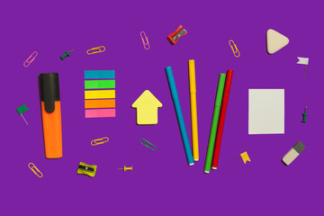 set of various school and office supplies lying on a purple background