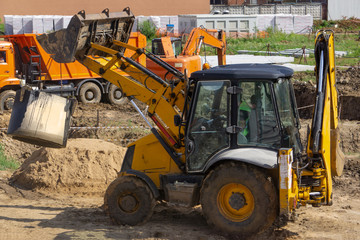 Tractor at the construction site carries a concrete ring for the well