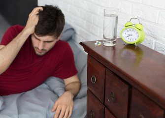 Man wake up with headache lying in bed