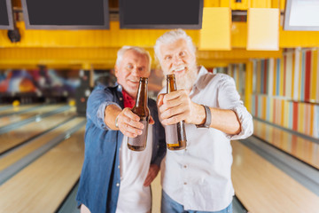 Fresh and cold. Selective focus of bottles of beer being held by joyful happy friends in the...