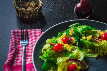 Salad with mango, cucumber and cherry tomatoes on black table close-up
