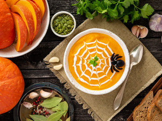 Funny food for Halloween. Pumpkin puree soup, spider web, dark old wooden table, top view.