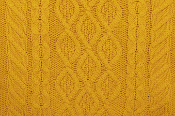 The texture of an orange autumn sweater. Knitted background. Knitted texture. A sample of knitting from wool.