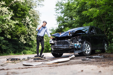 Mature man standing by the car, making a phone call after a car accident.